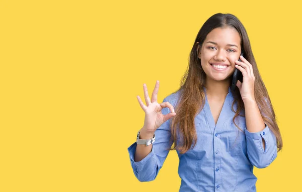年轻美丽的黑发女商人在智能手机上谈论孤立的背景做确定的手指标志 优秀的象征 — 图库照片