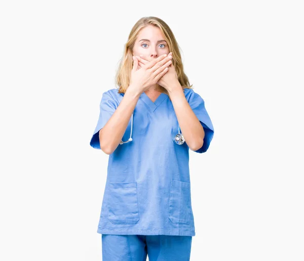 美丽的年轻医生妇女穿着医疗制服在孤立的背景震惊覆盖嘴与手的错误 秘密概念 — 图库照片