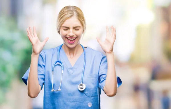 年轻美丽的金发医生护士护士妇女在孤立的背景庆祝疯狂和疯狂的成功与手臂抬起和闭上的眼睛尖叫兴奋 优胜者概念 — 图库照片