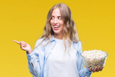 İzole arka tarafına el ve parmak ile işaret çok mutlu üzerinde patlamış mısır yemek güzel sarışın genç kadın