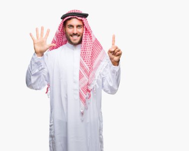 Keffiyeh üzerinde giyen genç yakışıklı adam arka plan gösteren izole ve parmakları ile işaret kendinden emin ve mutlu gülümseyerek süre 6 numara.