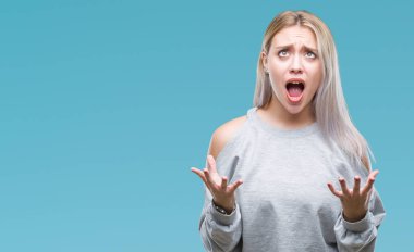 Sarışın genç kadın izole arka plan çılgın ve kızgın bağırarak ve agresif ifade ve silah kaldırdı bağırıyor. Hayal kırıklığı kavramı.