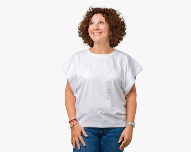Görünümlü yan ve dik dik bakma uzağa düşünce gülümseyen izole arka plan üzerinde beyaz t-shirt giyen güzel orta ager üst düzey kadın.