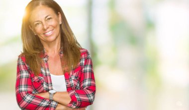 Orta yaş yetişkin kadın üzerinde rahat gömlek giymiş mutlu yüz ile gülümseyerek kameraya seyir silah geçti arka plan izole. Olumlu bir kişi.