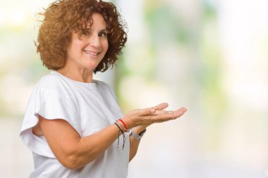 Arka plan üzerinde beyaz t-shirt giyen kadın güzel orta ager kıdemli izole el ve reklam mutlu ve kendinden emin gülümseyen sunulması avuç, yanında işaret