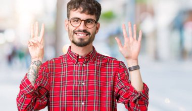 Gösterilen arka plan üzerinde gözlük takan genç yakışıklı adam izole ve parmakları ile işaret kendinden emin ve mutlu gülümseyerek süre 8 numaralı.