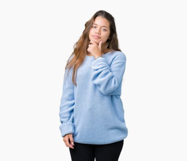 Üzerinde mavi kış kazak giyen genç güzel esmer kadın arka plan emin çapraz kollar ve çeneme kaldırdı el ile gülümseme ile kameraya bakarak izole. Pozitif düşünce.