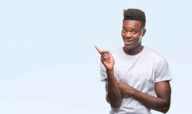 Kameraya bakarak yan el ve parmak ile işaret eden genç Afro-Amerikan adam yüzünde kocaman bir gülümseme ile izole arka plan üzerinde.
