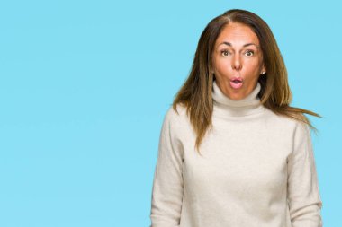 Güzel orta yaş yetişkin kadın giyiyor kış kazak korkuyor ve şok sürpriz ifade ile izole arka plan üzerinde korku ve yüz heyecanlı.