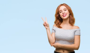 Genç güzel kadın mutlu yüz zafer işareti yaparken kameraya göz kırpıyor ile gülümseyen izole arka plan yüzünden. İki numaralı.