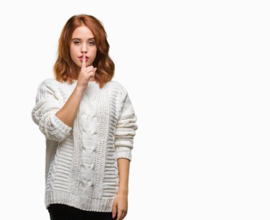 İzole arka plan dudaklarında parmak ile sessiz olmanı kış kazak giyen genç güzel kadın. Sessizlik ve gizli kavramı.