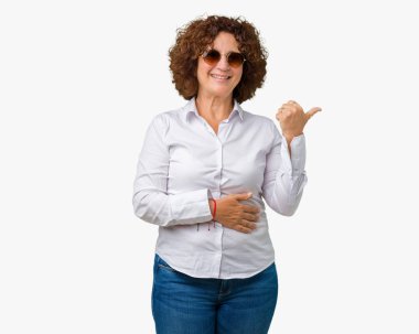 Güzel orta ager üst düzey iş kadını arıyor ve başparmak yanında yukarıyı mutlu yüz ile gülümseyen izole arka plan üzerinde güneş gözlüğü takıyor.
