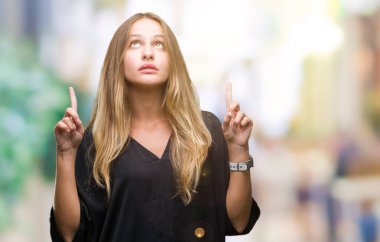 Genç güzel sarışın kadın izole arka plan üzerinden hayran ve yukarıya bakıp parmakları ile işaret şaşırttı ve silah kaldırdı.