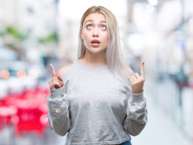 Sarışın genç kadın izole arka plan üzerinden hayran ve yukarıya bakıp parmakları ile işaret şaşırttı ve silah kaldırdı.