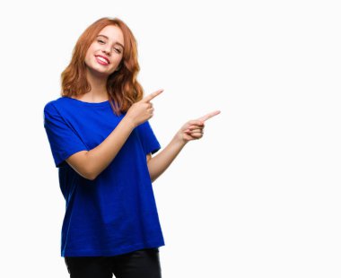 Gülümseyen ve iki elleri ve parmakları ile tarafına işaret kamera bakarak izole arka plan üzerinde genç güzel kadın.