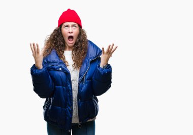 Güzel genç esmer kıvırcık saçlı kız izole arka plan çılgın ve kızgın bağırarak ve agresif ifade ve silah kaldırdı bağırmaya kış ceket, yün kap ve kazak giyiyor. Hayal kırıklığı kavramı.