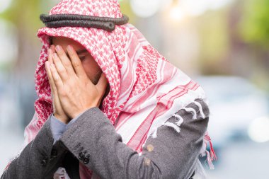 Uzun saçlı keffiyeh yüz eller ile ağlayarak süre kapsayan üzgün ifade ile izole arka plan üzerinde giyen genç yakışıklı Arap adam. Depresyon kavramı.