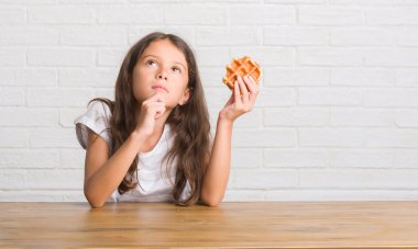 Gözleme ciddi bir yüz düşünme hakkında soru, çok yemek masada oturan genç İspanyol çocuğun fikir karışık