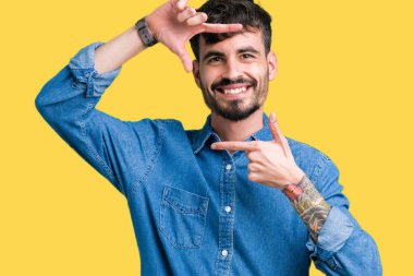 Yakışıklı delikanlı elle yapma çerçeve ve parmakları ile mutlu yüz gülümseyen izole arka plan üzerinde. Yaratıcılık ve Fotoğrafçılık kavramı.