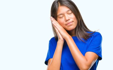 Uyku yorgun hayal ve ellerle birlikte poz ile kapalı gözler gülümseyen izole arka plan üzerinde Genç Asyalı kadın.