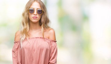 Yüzünde ciddi bir ifade ile izole arka plan üzerinde Retro güneş gözlüğü takıyor güzel sarışın genç kadın. Basit ve doğal kameraya bakıyor.