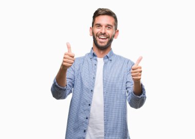 Yakışıklı delikanlı izole arka plan başarı işareti el ile pozitif jest yapıyor üzerinde beyaz t-shirt giyen başparmak gülümseyen ve mutlu. Neşeli bir ifadeyle, kazanan jest kameraya bakıyor.