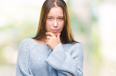 Emin çapraz kollar ve çeneme kaldırdı el ile gülümseme ile kameraya bakarak izole arka plan üzerinde kış kazak giyen genç güzel beyaz kadın. Pozitif düşünce.