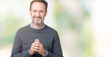 Üzerinde bir kazak giyen yakışıklı orta yaş üst düzey adam arka plan eller birlikte izole ve rahat ve neşeli gülümseyen parmak çarpı işareti. Başarı ve iyimser