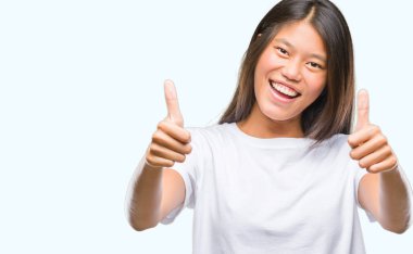 Genç Asyalı kadın el ile pozitif jest yapıyor onaylama izole arka plan üzerinde başparmak gülümseyen ve başarı için mutlu. Kamera, kazanan jest arıyorsunuz.