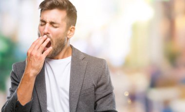 Genç yakışıklı iş adamı izole arka esneme sıkılmış üzerinde kaplama ağız el ile yorgun. Restless ve uyku hali.