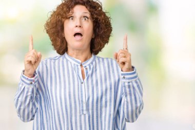 Hayret ve yukarıya bakıyor ve parmakları ile işaret ve silah kaldırdı sürpriz arka plan üzerinde Donanma forması giyen güzel orta ager üst düzey kadın izole.