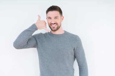 Genç yakışıklı adam giyen sıradan kazak yapıyorsun gülümseyen izole arka plan üzerinde telefon hareketi ile el ve parmak telefonda konuşuyor gibi. Kavramları iletişim.