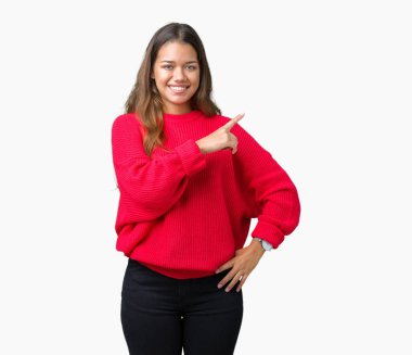 Üzerinde izole kırmızı kış kazak giyen genç güzel esmer kadın yan gösteren reklam, ciddi ve sakin yüz el parmak ile işaret arka plan