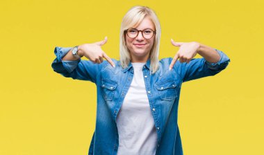 Yüzünde gülümseme ile kendinden emin görünüyorsun, kendini gururlu ve mutlu parmakları ile işaret izole arka plan üzerinde gözlük takan genç güzel sarışın kadın.