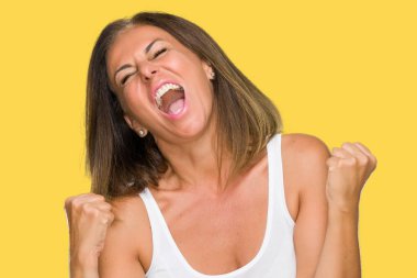 Gülümseyen ve başarı için çığlık güzel orta yaş rahat yetişkin kadın izole arka plan çok mutlu ve heyecanlı kaldırdı, silah ile kazanan jest yapıyor. Kutlama kavramı.