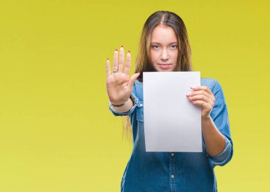 Boş kağıt sayfası ile izole arka plan üzerinde tutan genç beyaz kadın dur işareti ile ciddi ve kendine güvenen ifade, savunma hareketi yaparken el açmak