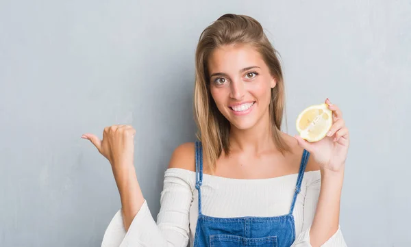 Krásná Mladá Žena Grunge Šedá Zeď Drží Citron Polohovací Zobrazení — Stock fotografie