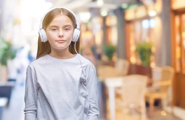 年轻漂亮的女孩戴着耳机听音乐 在孤立的背景下 面部表情严肃 简单而自然地看着相机 — 图库照片