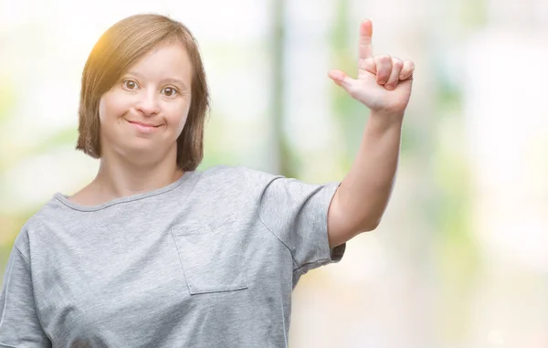 年轻的成年妇女与唐氏综合征在孤立的背景显示和指向的手指第二 而微笑着自信和快乐 — 图库照片