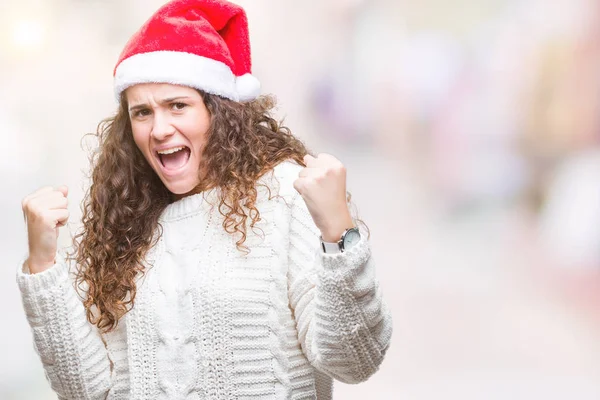 年轻的黑发女孩在孤立的背景上戴着圣诞帽 非常高兴和兴奋地做了胜利的手势 双臂抬起 面带微笑 尖叫着要成功 庆祝理念 — 图库照片