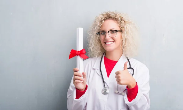 Joven Rubia Médico Mujer Sobre Grunge Gris Pared Celebración Grado —  Fotos de Stock