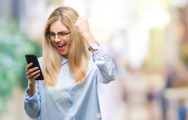 Young beautiful blonde business woman using smartphone over isolated background annoyed and frustrated shouting with anger, crazy and yelling with raised hand, anger concept