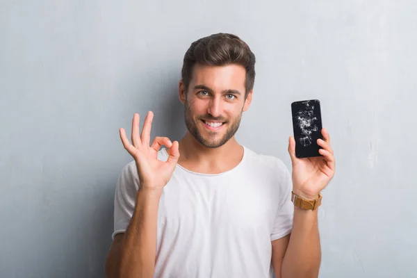 Handsome Young Man Grey Grunge Wall Showing Broken Smartphone Screen — Stock Photo, Image