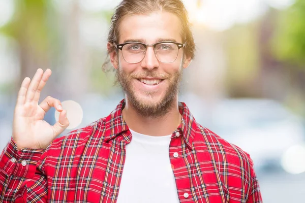 孤立した背景を浮かべて手と指で サインをしている肯定的な上眼鏡長い髪の若いハンサムな男 成功した式 — ストック写真