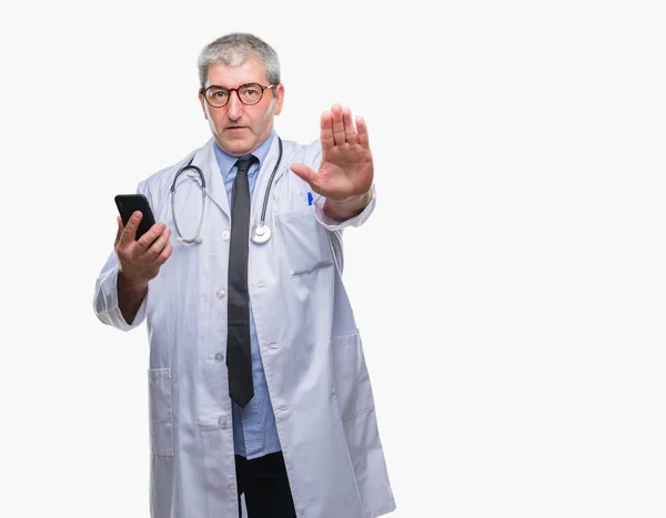 英俊的资深医生在孤立的背景下用智能手机发短信 张开手做停止签名 用严肃而自信的表情 防御手势 — 图库照片