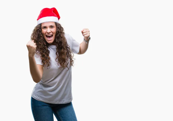 笑顔と成功のために叫んで 上クリスマスの帽子を着ている若いブルネットの少女は非常に幸せと興奮の腕を上げ 勝者のジェスチャを行う背景を分離しました お祝いのコンセプト — ストック写真