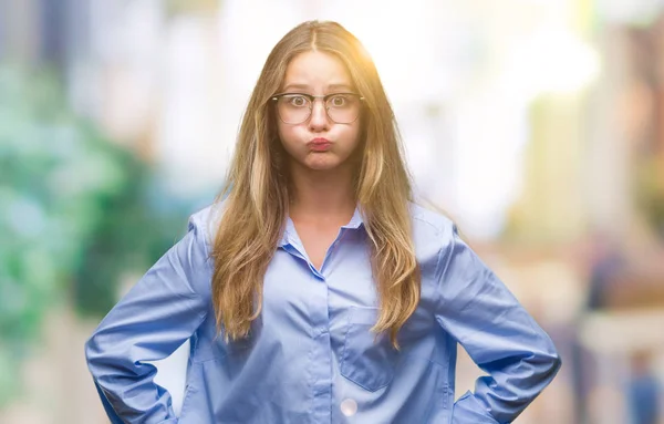 Young beautiful blonde business woman wearing glasses over isolated background puffing cheeks with funny face. Mouth inflated with air, crazy expression.