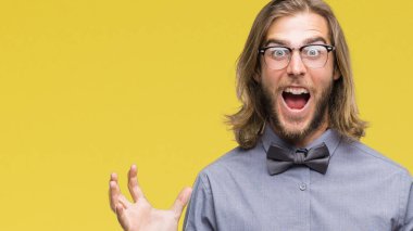 Üzerinde papyon giyiyor uzun saçlı yakışıklı delikanlı deli kutluyor arka plan izole ve başarı için kaldırdı kollarını açarak hayrete ve heyecanlı çığlık gözleri açık. Kazanan kavramı