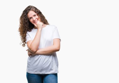 Güzel esmer kıvırcık saçlı Genç kız emin çapraz kollar ve çeneme kaldırdı el ile gülümseme ile kameraya bakarak izole arka plan üzerinde rahat t-shirt giyiyor. Pozitif düşünce.