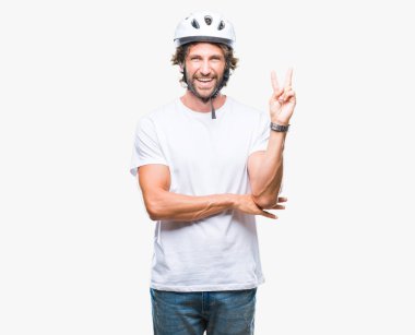 Mutlu yüz zafer işareti yaparken kameraya göz kırpıyor ile gülümseyen izole arka plan üzerinde güvenlik kask giyen yakışıklı İspanyol bisikletçi adam. İki numaralı.